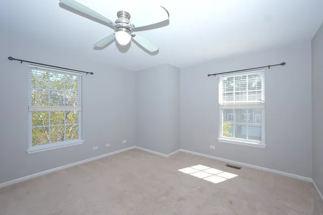 an empty room with windows and fan