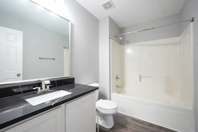 a bathroom with a granite countertop sink toilet and shower