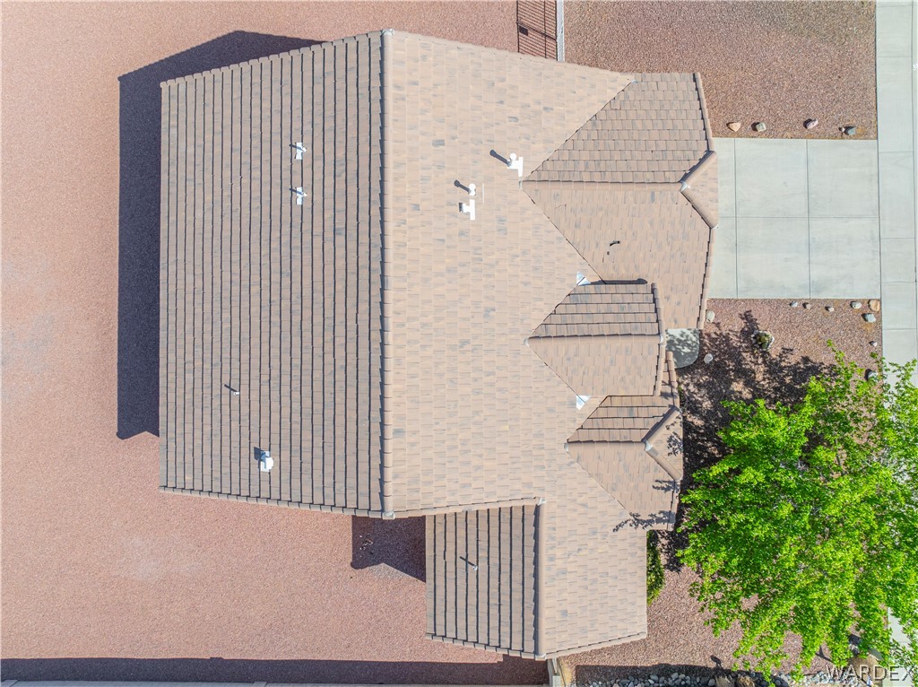 3973 Prairie View Drive Kingman, AZ 86409 - Photo 6 of 34 Aerial view of the property featuring a brown shingle roof, a paved driveway, and landscaping with gravel and a mature tree
