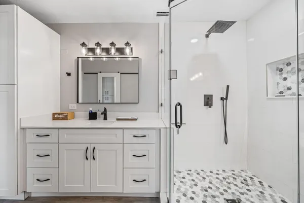 a bathroom with a sink a toilet a shower and a mirror