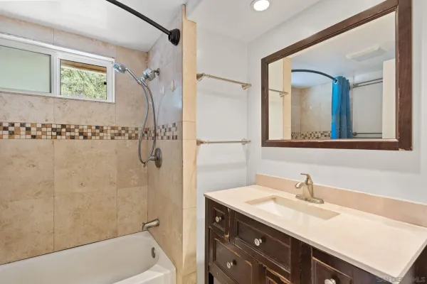 a bathroom with a granite countertop sink a mirror a vanity a shower and a bathtub