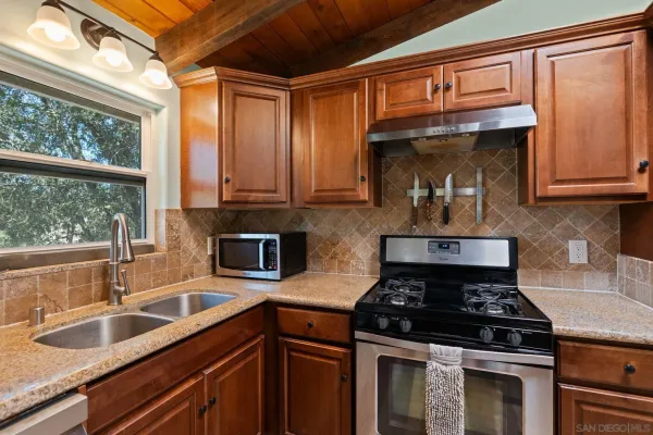 a kitchen with granite countertop wooden cabinets stove top oven and sink