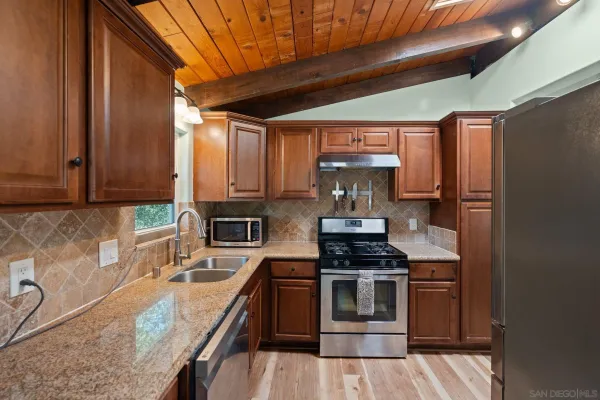 a kitchen with stainless steel appliances granite countertop a stove a sink and a microwave