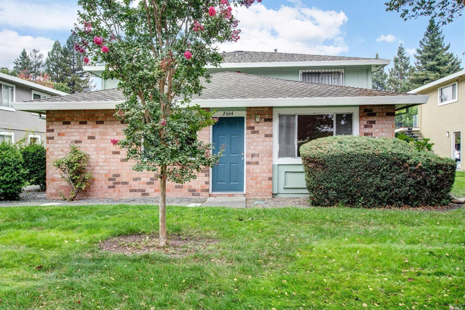 a brick house with a small yard and big trees