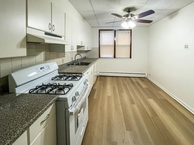 a kitchen with a stove a sink and wooden floor