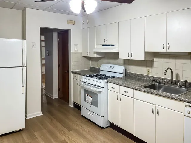 a kitchen with stainless steel appliances granite countertop white cabinets a sink a stove a refrigerator and white cabinets