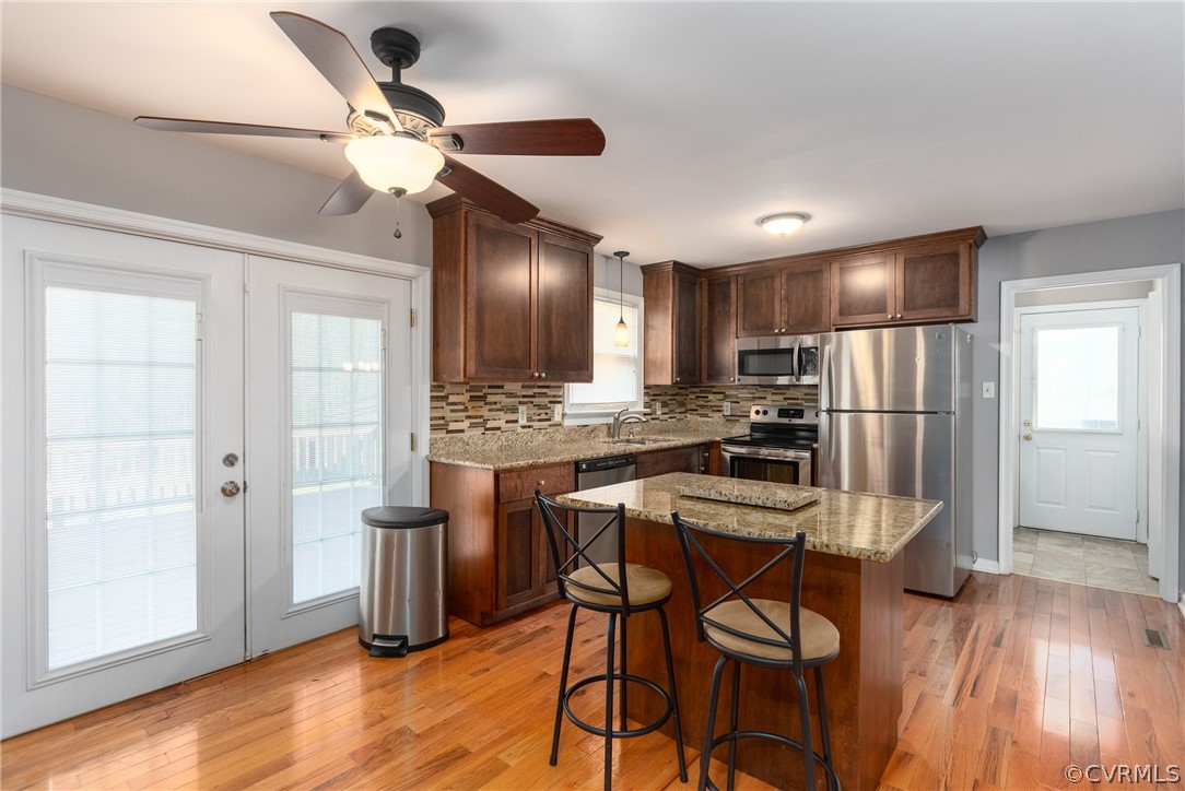 10200 Ambridge Road Chesterfield, VA 23832 - Photo 6 of 36 a kitchen with kitchen island granite countertop wooden floors white cabinets and stainless steel appliances