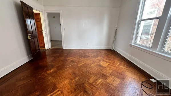 a view of an empty room with window and wooden floor