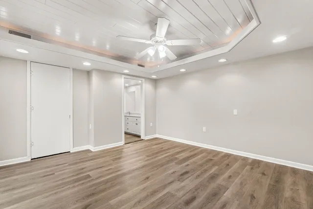 an empty room with wooden floor chandelier fan and closet area