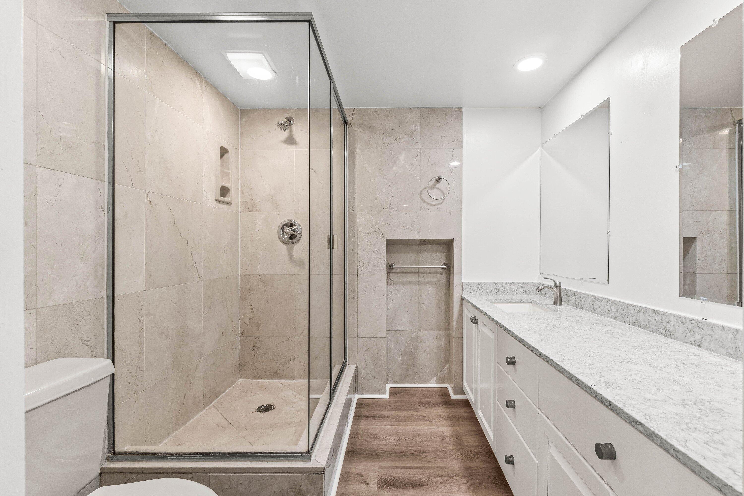 2905 Southwest 22nd Circle, Unit 40A Delray Beach, FL 33445 - Photo 15 of 38 a bathroom with a granite countertop sink a mirror a shower and a bathtub