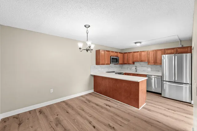 a kitchen with stainless steel appliances granite countertop a sink a stove a refrigerator and island with wooden floor