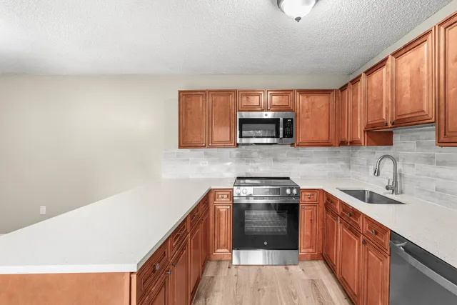 a kitchen with a sink a stove top oven and wooden floor