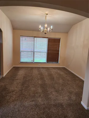 a view of an empty room with chandelier and a fireplace
