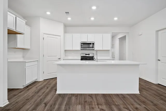 a kitchen with kitchen island white cabinets and stainless steel appliances