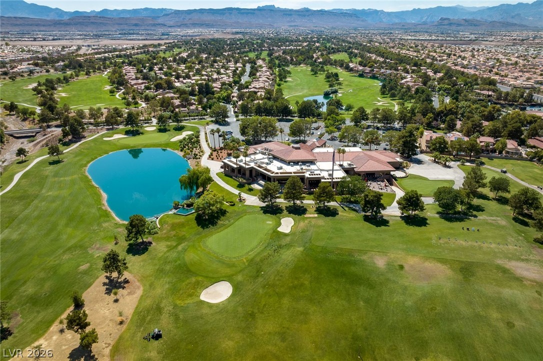 20 Innisbrook Avenue Las Vegas, NV 89113 - Photo 26 of 39 An aerial perspective reveals a vast golf course, complete with a shimmering lake and clubhouse, set against a backdrop of distant mountains.