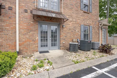 a view of a brick house with potted plants and a table and chair