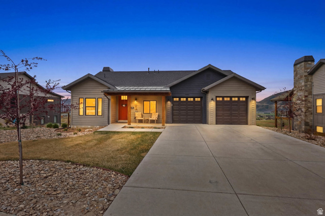 View of front of property featuring covered porch, a front yard, concrete driveway, a garage, and a shingled roof