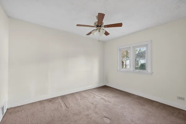 an empty room with a window and a fan