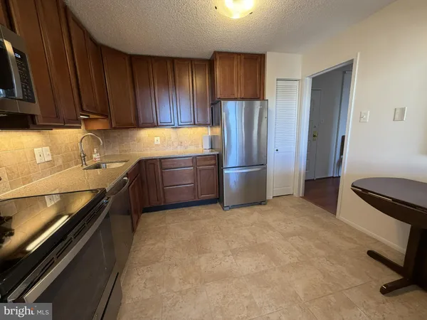 a kitchen with granite countertop a refrigerator and a stove top oven