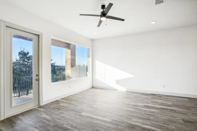 a view of empty room with wooden floor and fan