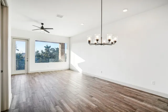 an empty room with wooden floor ceiling fan and window