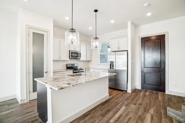 a kitchen with a refrigerator a sink and a wooden floor