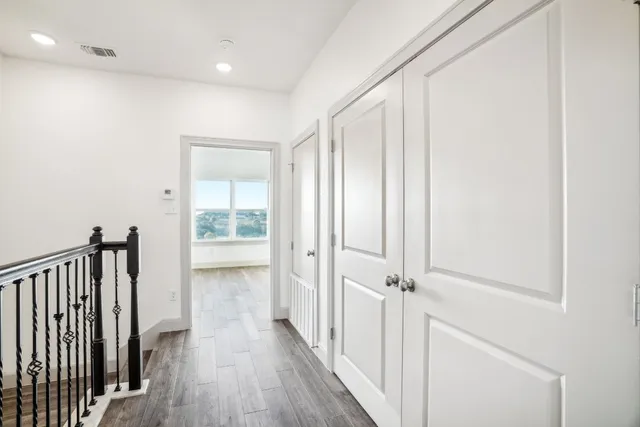 a view of a hallway with wooden floor and a bathroom