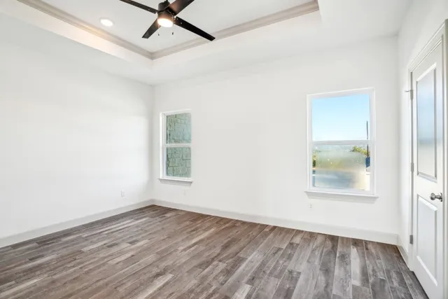 an empty room with wooden floor and windows