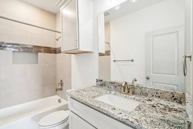 a bathroom with a granite countertop sink toilet and shower