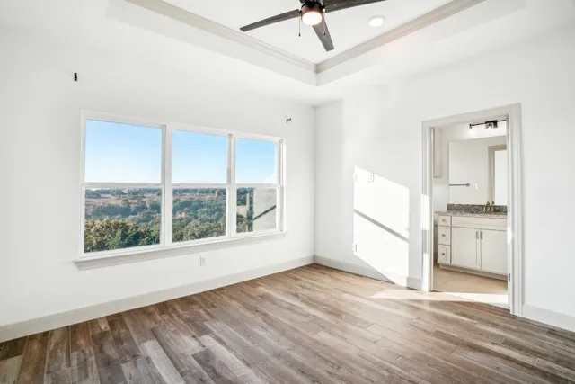 a view of empty room with wooden floor and fan
