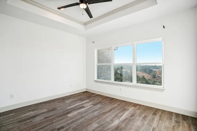 an empty room with wooden floor fan and windows