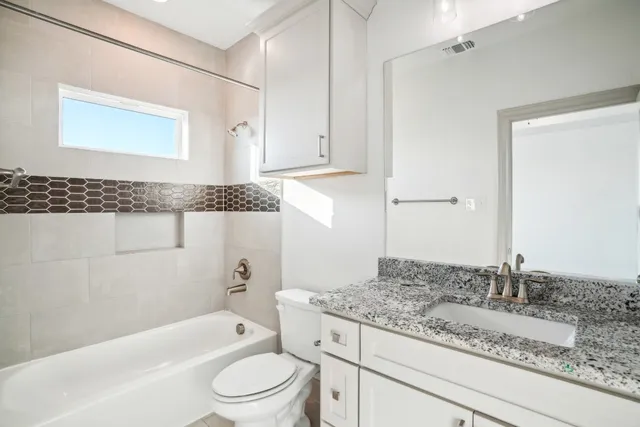 a bathroom with a granite countertop sink a toilet and bathtub