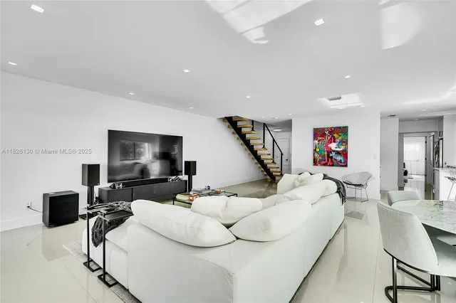 a living room with furniture a flat screen tv and kitchen view