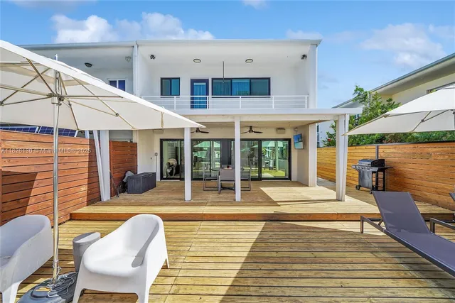a view of a patio with couches table and chairs under an umbrella