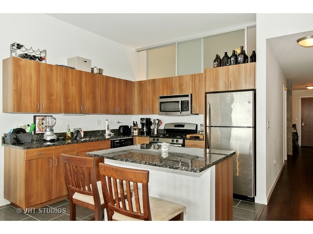 235 West Van Buren Street, Unit 4606 Chicago, IL 60607 - Photo 9 of 22 a kitchen with stainless steel appliances granite countertop a refrigerator a stove a sink and white cabinets with wooden floor