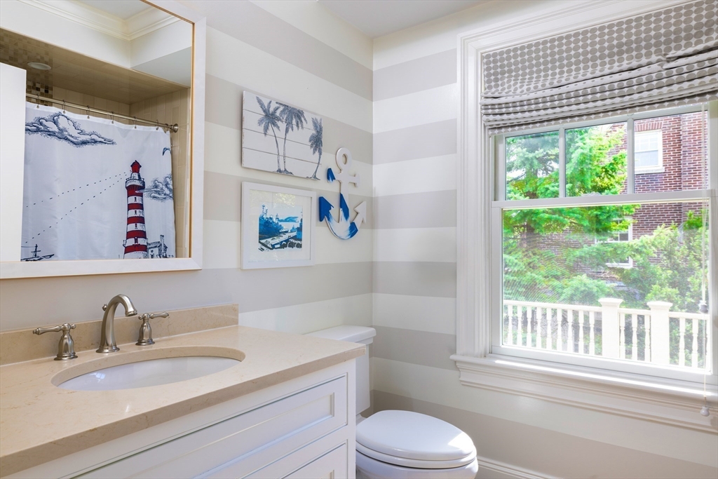 1004 Centre Street Newton, MA 02459 - Photo 25 of 34 a bathroom with a granite countertop toilet a sink a shower curtain and a large window