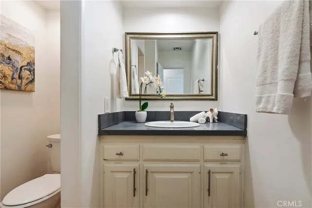 a bathroom with a granite countertop sink and a toilet