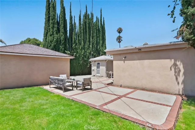 a backyard of a house with table and chairs potted plants and a floor to ceiling window