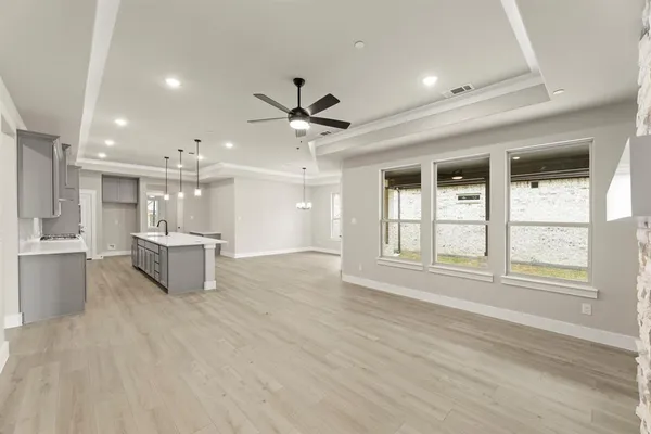 a view of an empty room with a window and kitchen view