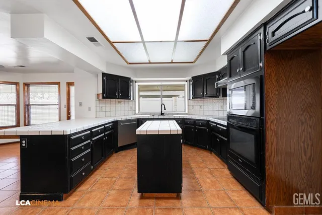 a kitchen with kitchen island granite countertop stainless steel appliances and wooden cabinets