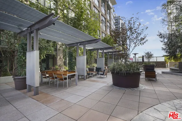 a view of a patio with couches table and chairs potted plants and large tree