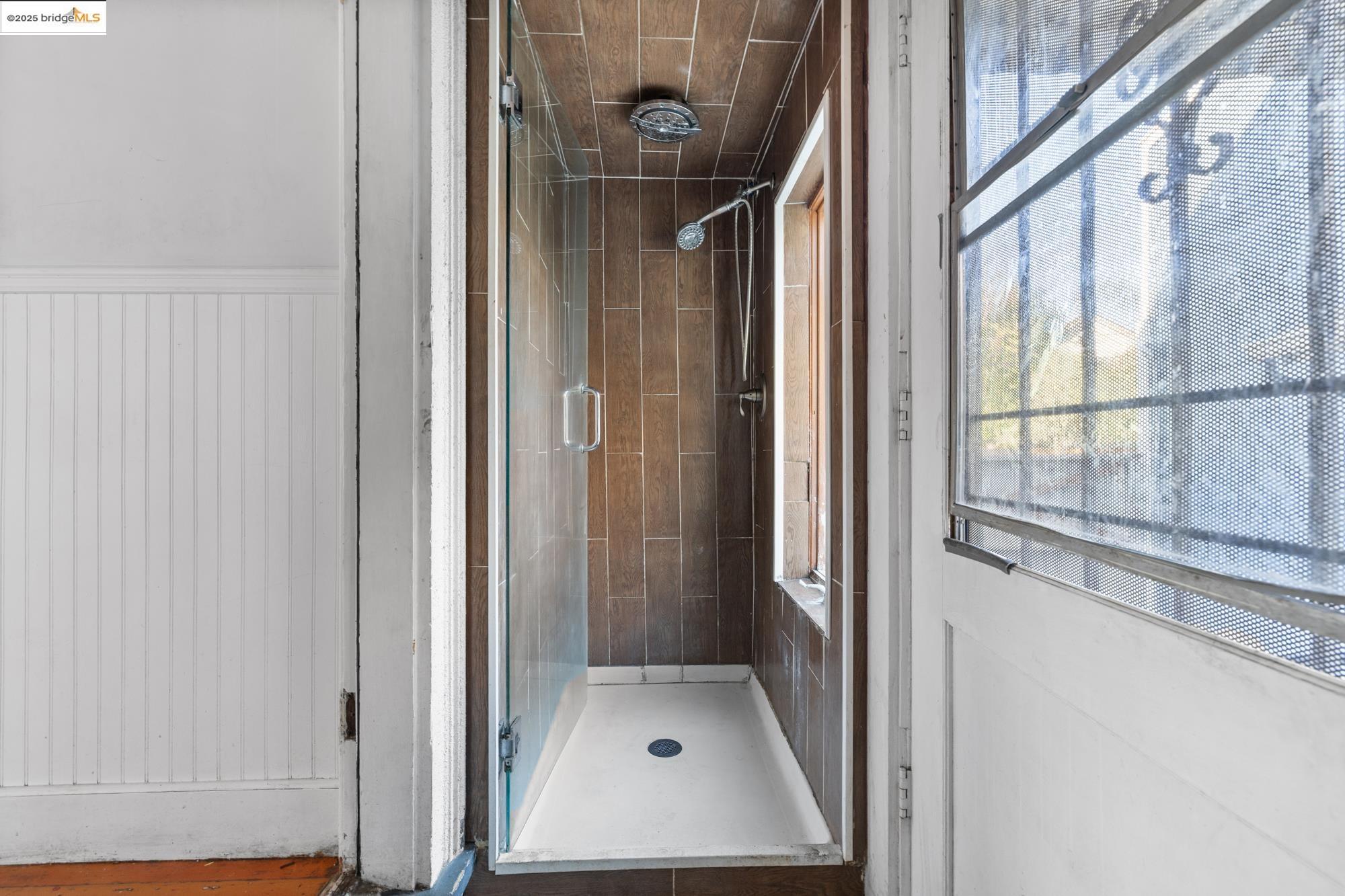 1746 8th Street Oakland, CA 94607 - Photo 15 of 52 a bathroom with a glass shower door and mirror