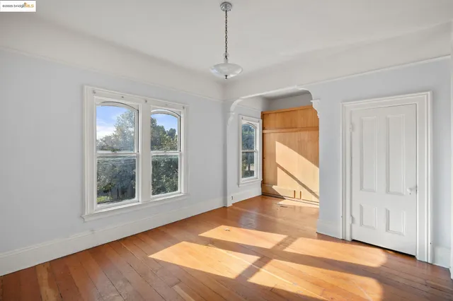 a view of an empty room with a window and wooden floor