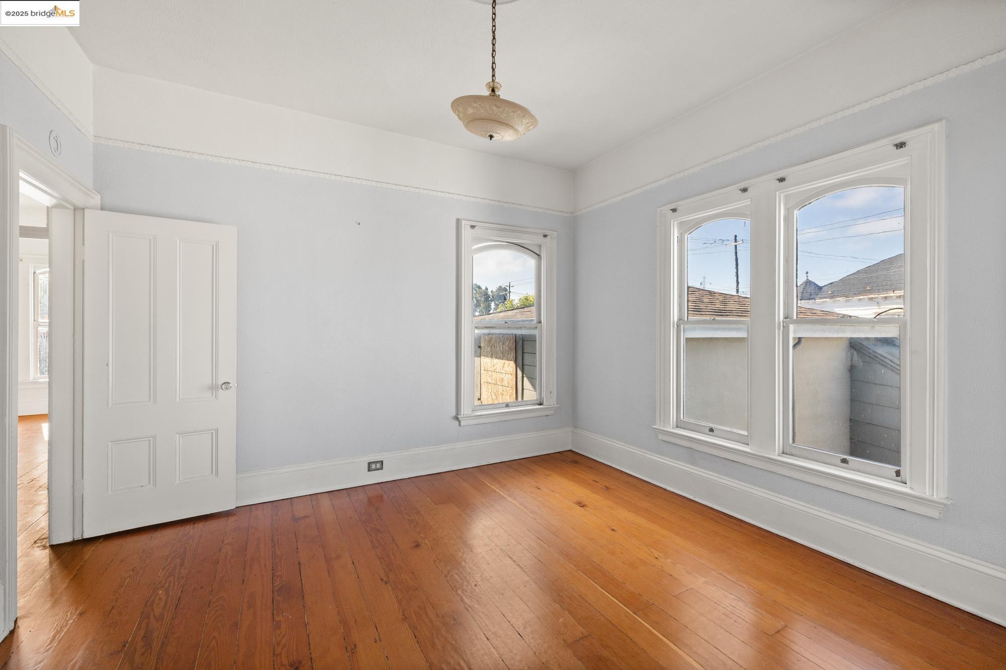 1746 8th Street Oakland, CA 94607 - Photo 25 of 52 an empty room with wooden floor and windows
