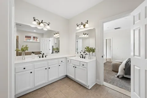 a spacious en suite bathroom with a double vanity sink and mirror