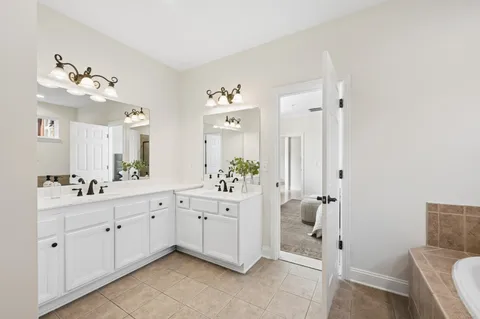 a spacious bathroom with a double vanity sink a mirror a bathtub and a shower