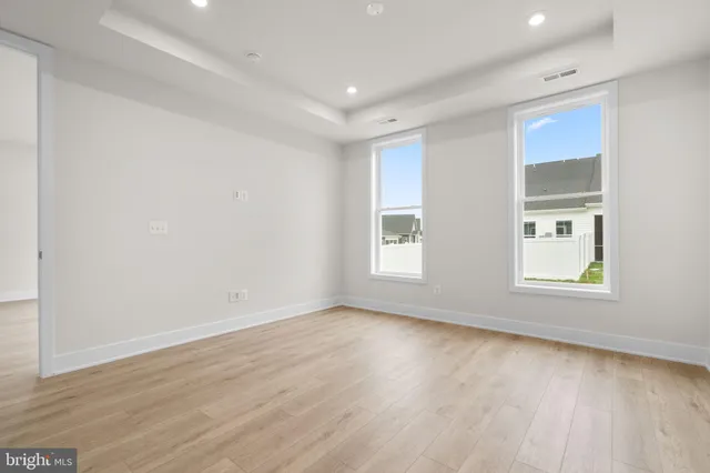an empty room with wooden floor and windows