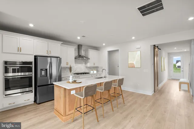 a kitchen with stainless steel appliances kitchen island granite countertop a refrigerator a stove a sink a dining table and chairs