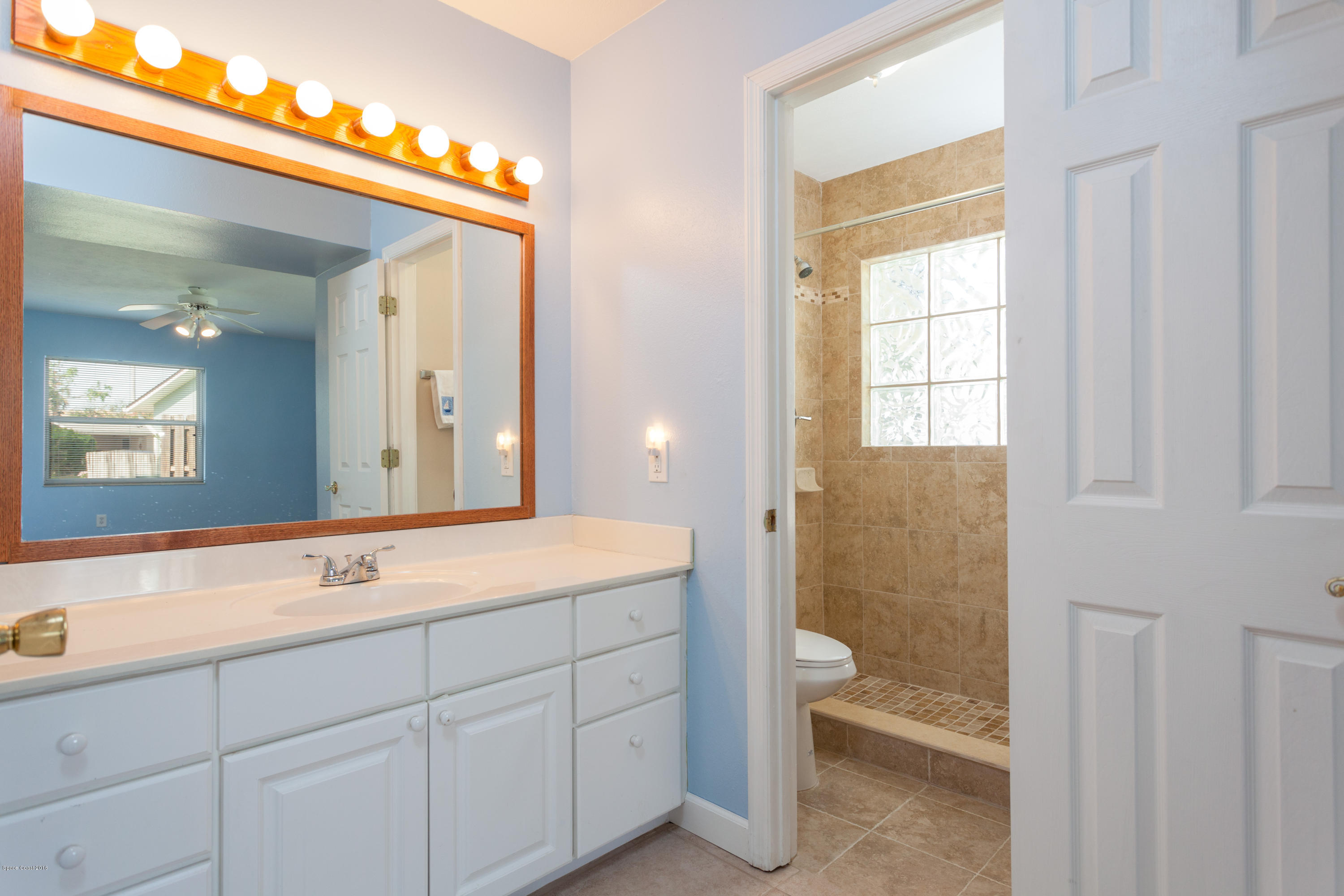 1035 Trinidad Road Cocoa Beach, FL 32931 - Photo 16 of 23 a bathroom with a sink a toilet and a large mirror