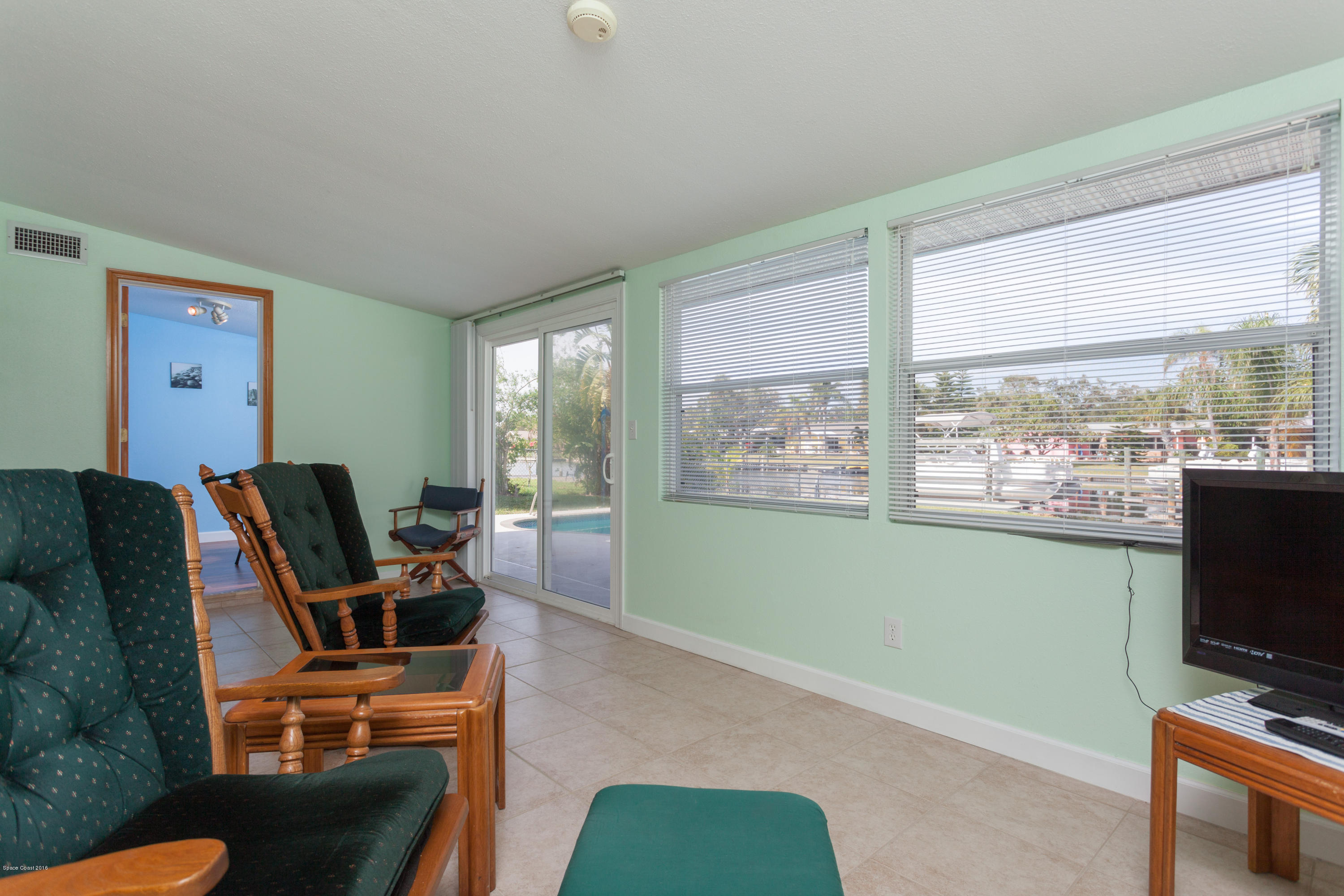 1035 Trinidad Road Cocoa Beach, FL 32931 - Photo 8 of 23 a living room with furniture a flat screen tv and a floor to ceiling window